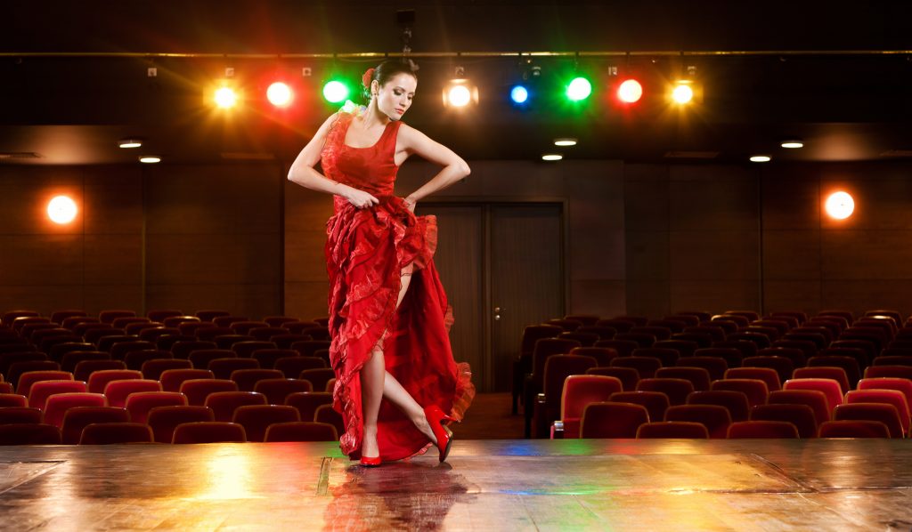 Sexy flamenco dancer performing her dance in a red long dress.