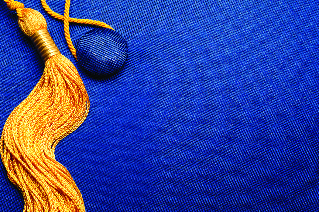 A close up of the top of a graduation cap. It is blue and has a gold tassel.
