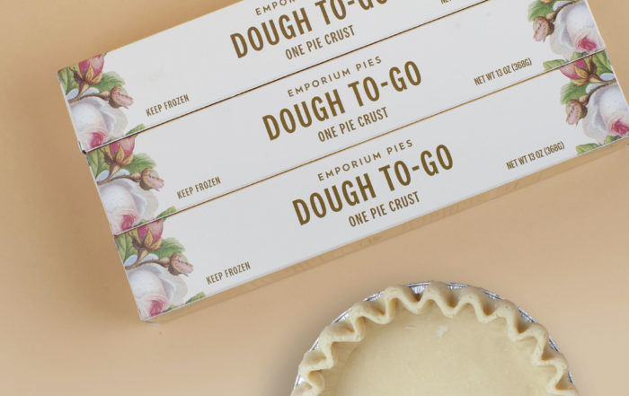 boxes of pie crust from Emporium Pies. A crust laid out in a pan is partially visible from the bottom of the image.